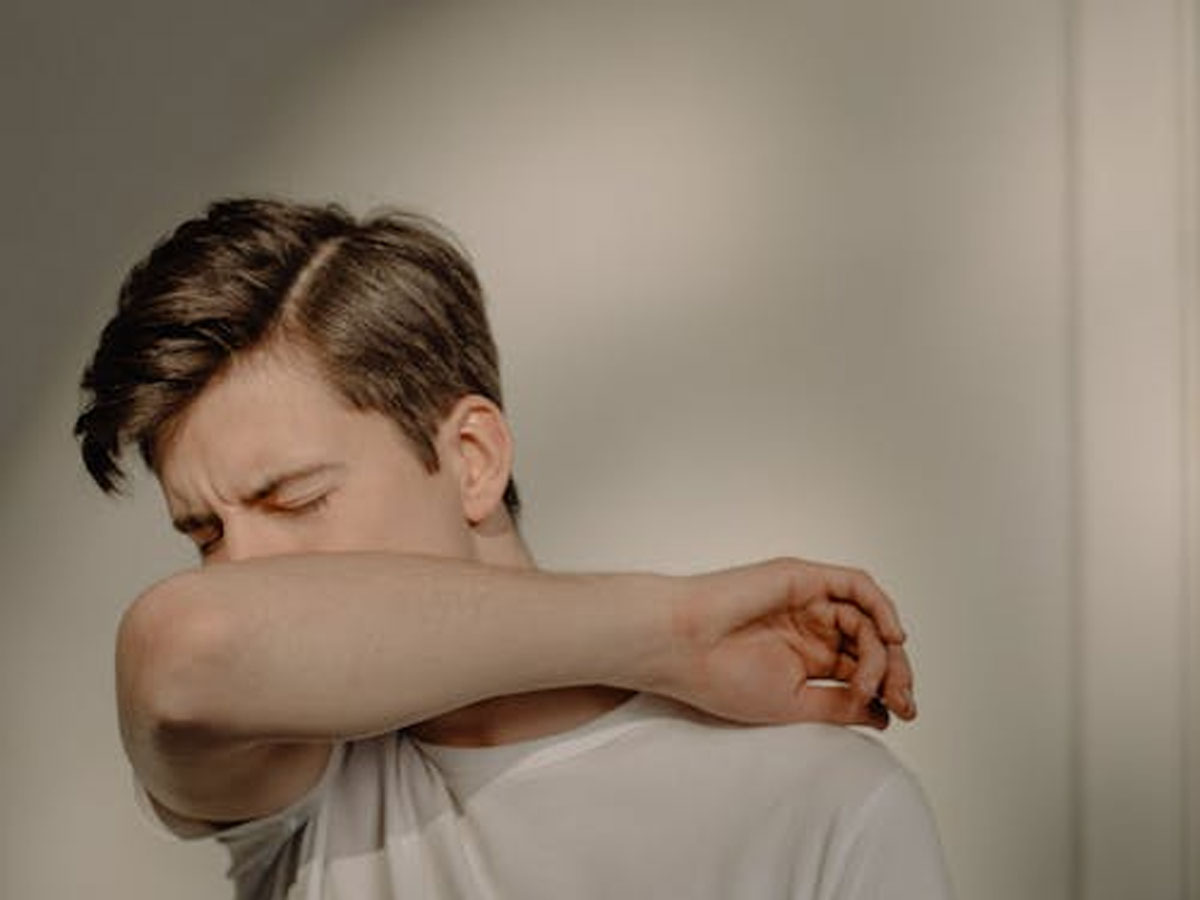 man sneezing coverring nose with hand